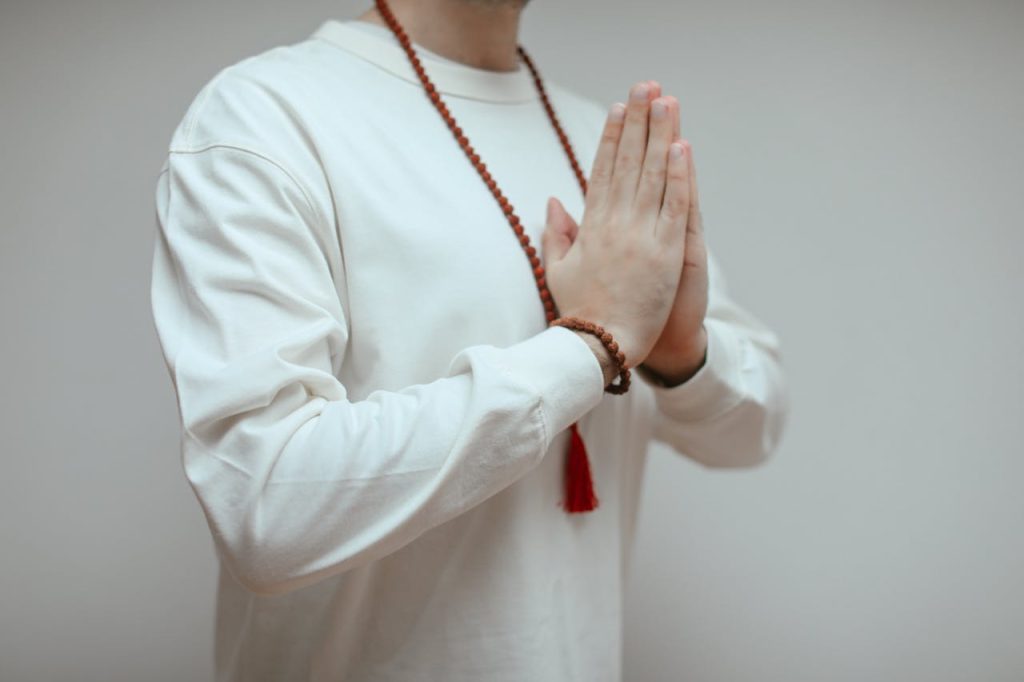 man-in-white-long-sleeve-shirt-in-praying-hands-6633926 A person in white long sleeves meditating with prayer beads.